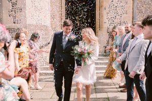Couple joyfuly walking through their wedding guests in a confetti tunnel | 5 Tips for wedding confetti