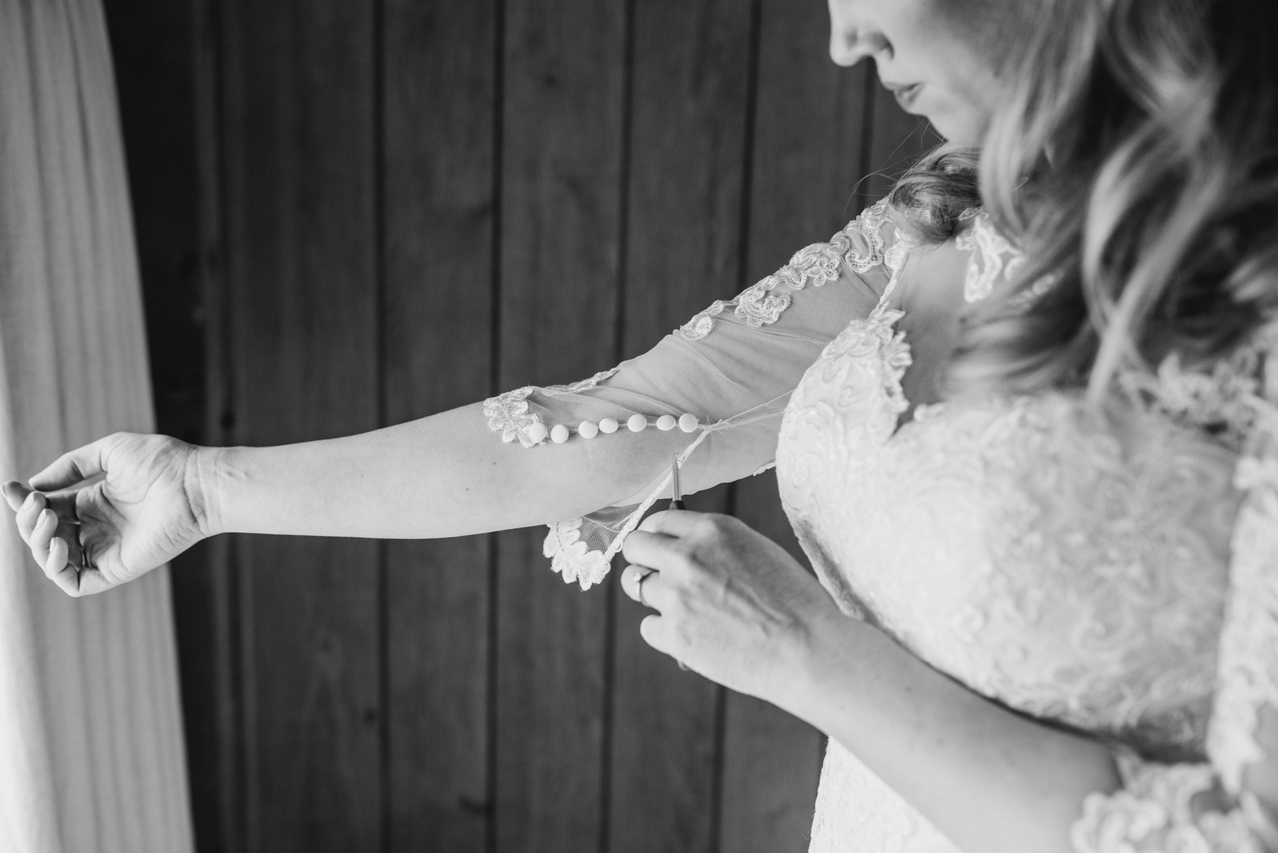 Black and White photo of Bride cutting a thread from her wedding dress sleeve | Wedding Survival Kit