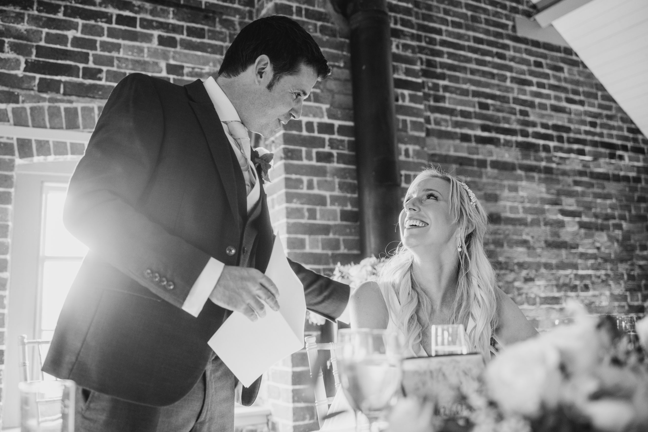 groom doing his wedding speech and smiling at his bride